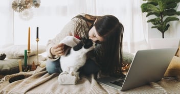 women kissing cat on bed with laptop out