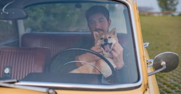 Dog and man sitting in yellow truck while the dog smiles with tongue out for TikTok video 
