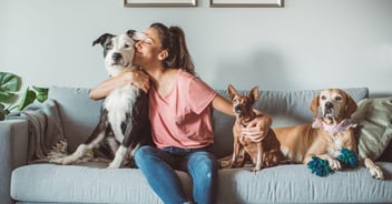 women on couch with her three dogs, with her arms around two of her dogs