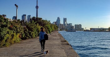 Women walking her small dog by waterside in Toronto, Ontario 